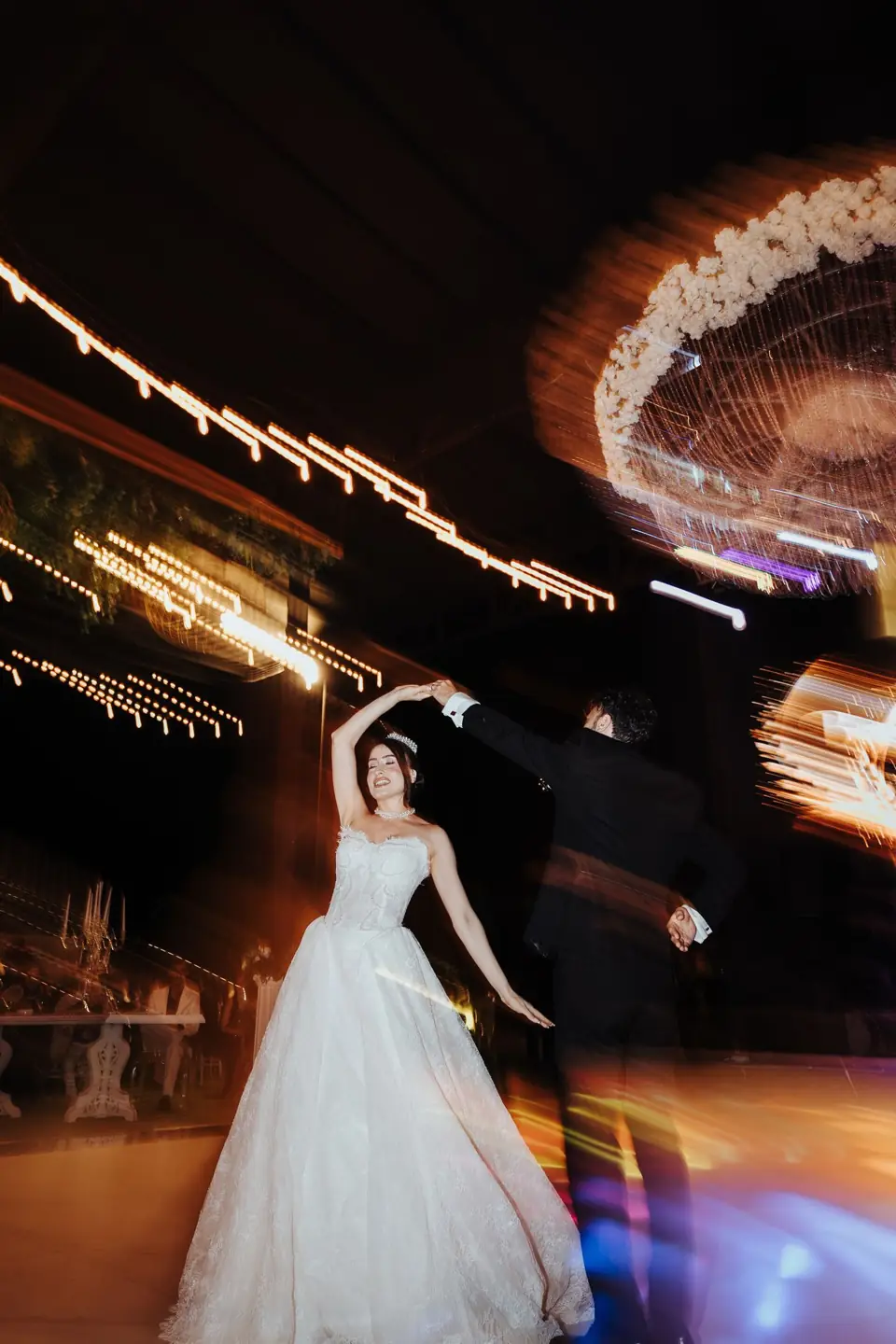 A bride spinning under lights, blurred with movement